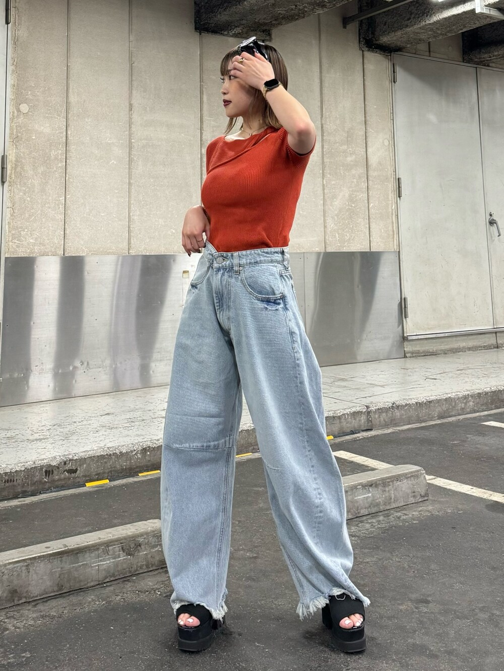 オレンジ系のニット/セーター、ブルー系のデニムパンツを着用したレディースの夏コーディネートの2枚目の写真