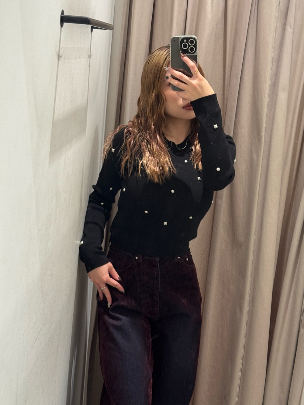レッド系のデニムパンツ、ブラック系のニット/セーター、ブラック系のブーツを着用したレディースの秋コーディネートの4枚目の写真