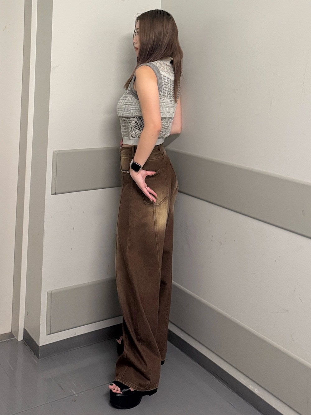 グレー系のタンクトップ、ブラウン系のデニムパンツ、ブラック系のサンダルを着用したレディースの夏コーディネートの2枚目の写真