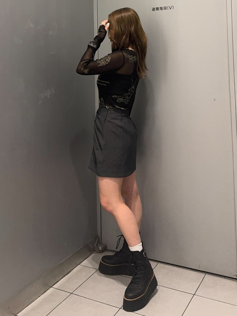 ブラック系のTシャツ/カットソー、グレー系のスカート、ブラック系のブーツを着用したレディースの秋コーディネートの2枚目の写真