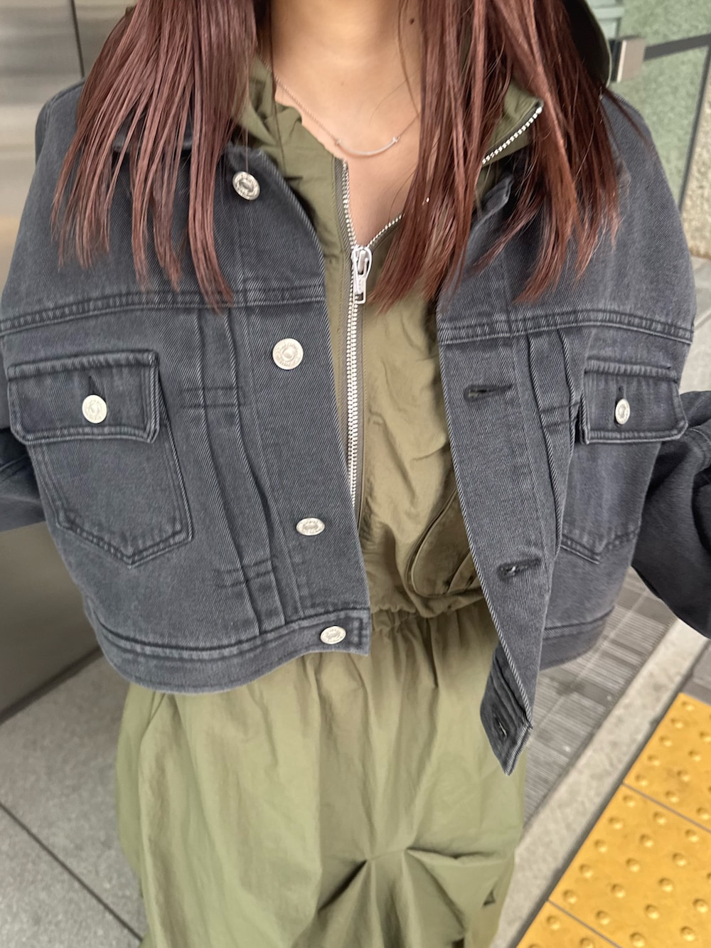 ブラック系のデニムジャケット、ベージュ系のベスト、グリーン系のスカートを着用したレディースの春コーディネートの5枚目の写真