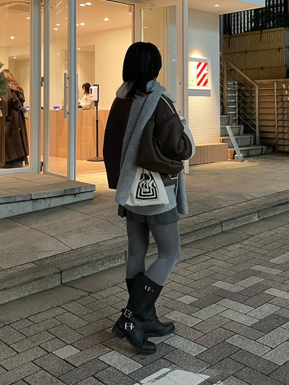 ブラウン系のムートンコート、グレー系のニット/セーター、ブラウン系のショルダーバッグを着用したレディースの冬コーディネートの4枚目の写真