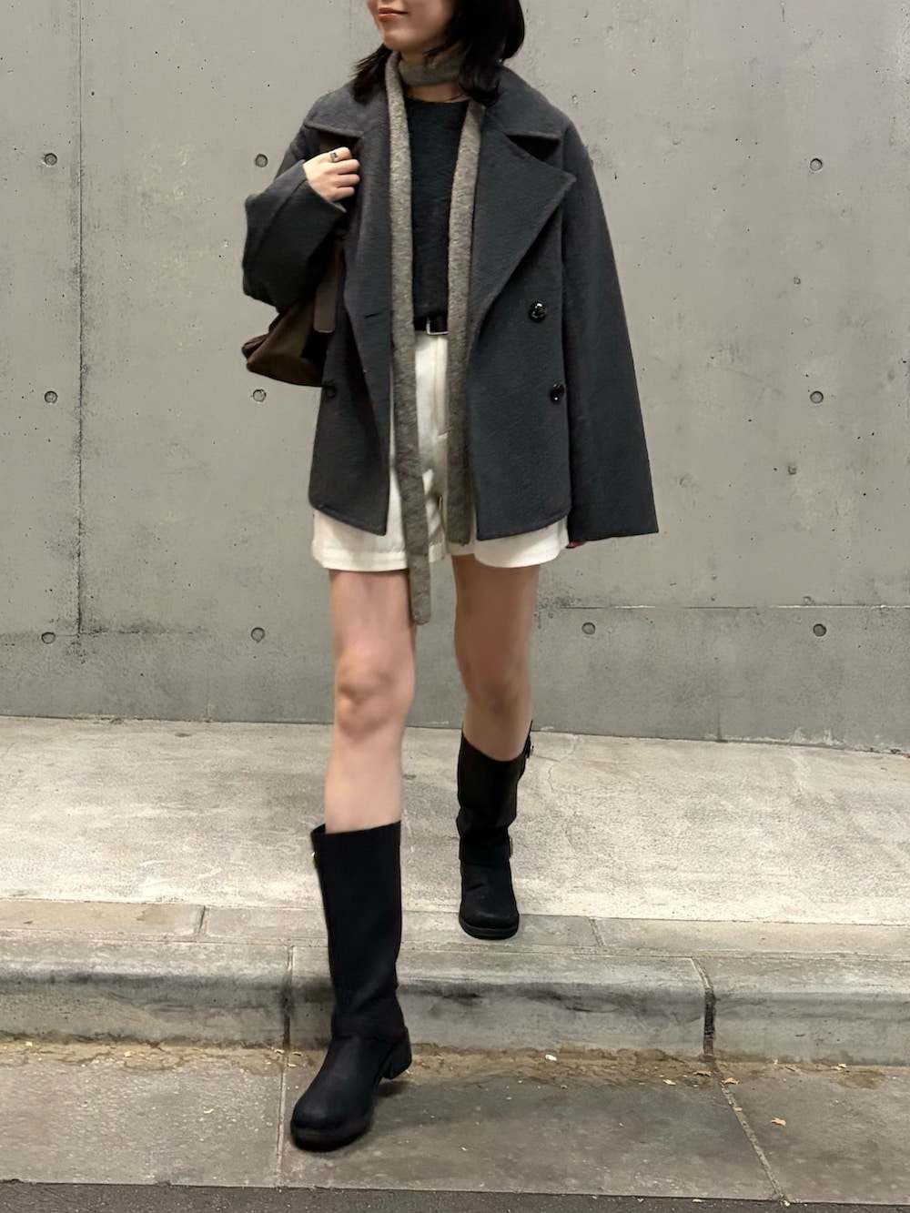 グレー系のピーコート、ブラウン系のショルダーバッグ、グレー系のニット/セーターを着用したレディースの冬コーディネートの2枚目の写真