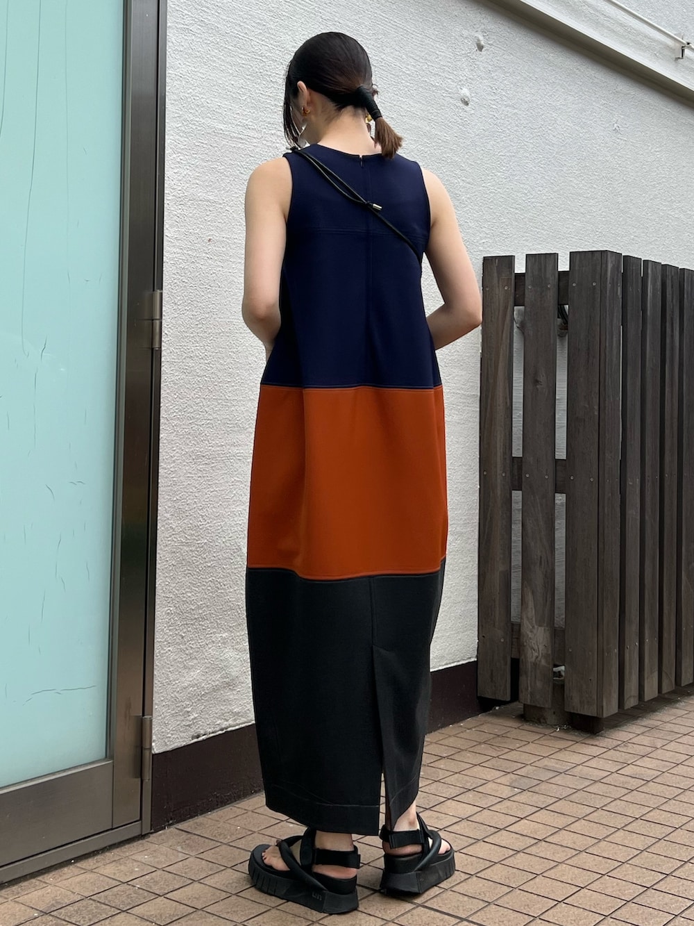 オレンジ系のワンピース、シルバー系の財布、シルバー系のイヤリングを着用したレディースの春コーディネートの3枚目の写真