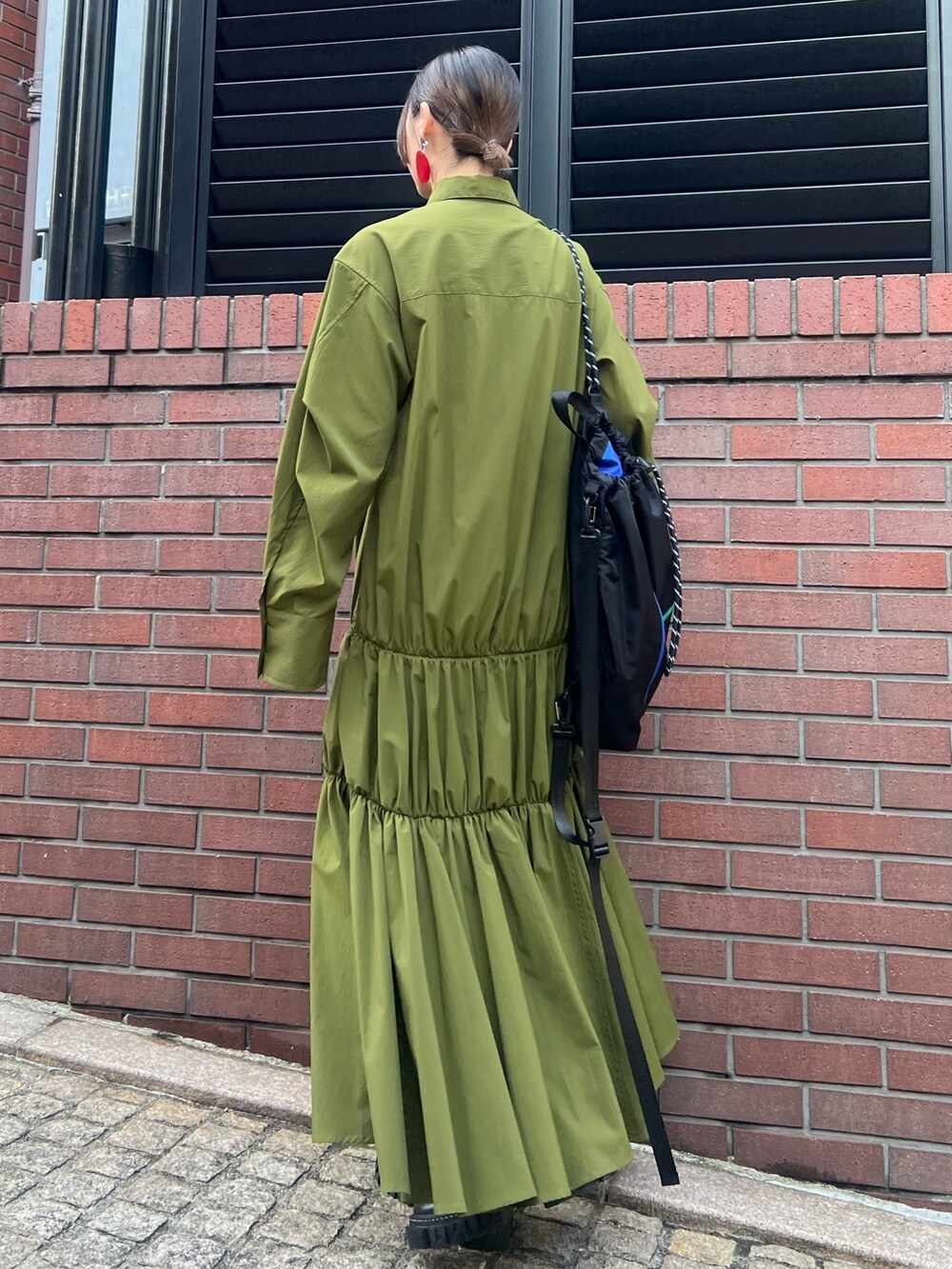 グリーン系のワンピース、ブラック系のブーツ、レッド系のイヤリングを着用したレディースの冬コーディネートの3枚目の写真