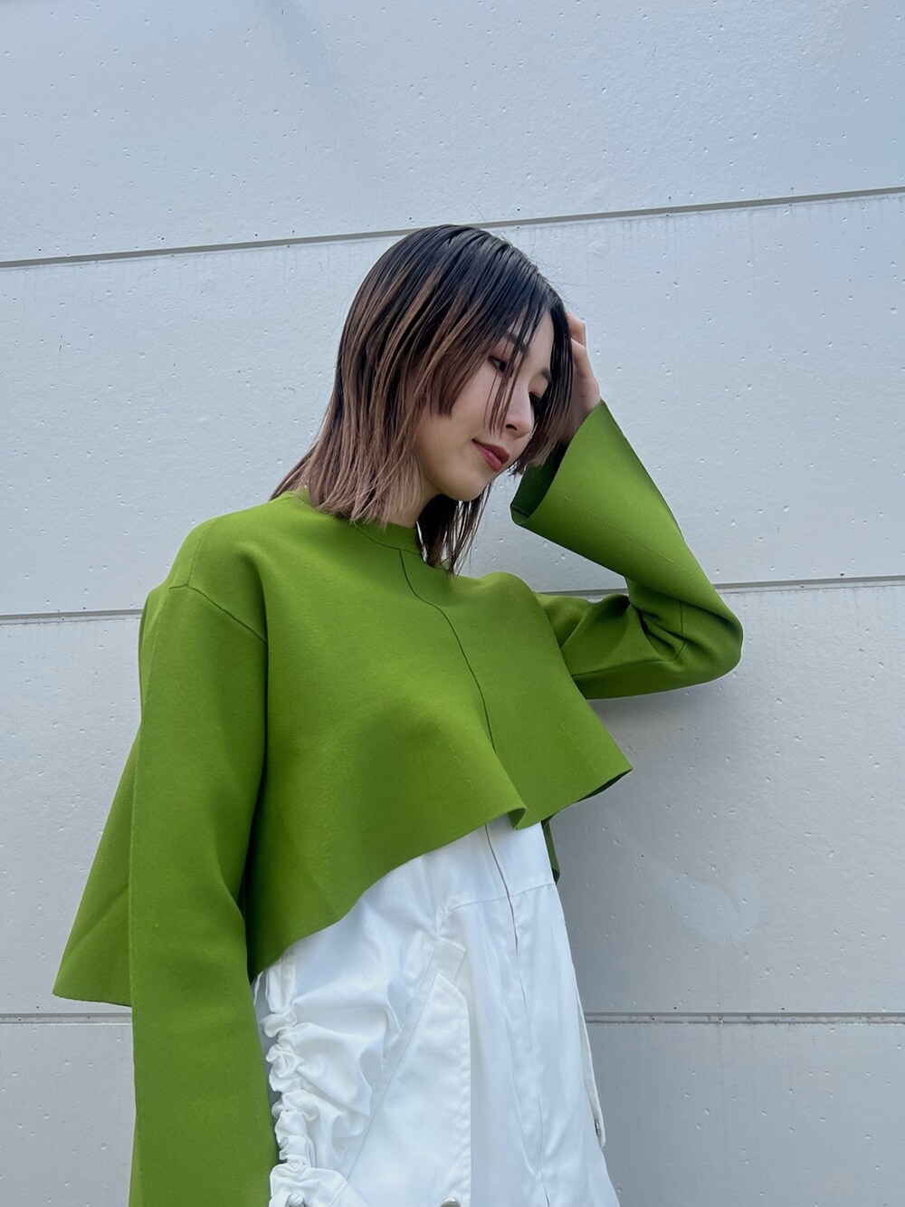 ホワイト系のスカート、グリーン系のニット/セーター、ブラック系のショルダーバッグを着用したレディースの冬コーディネートの3枚目の写真