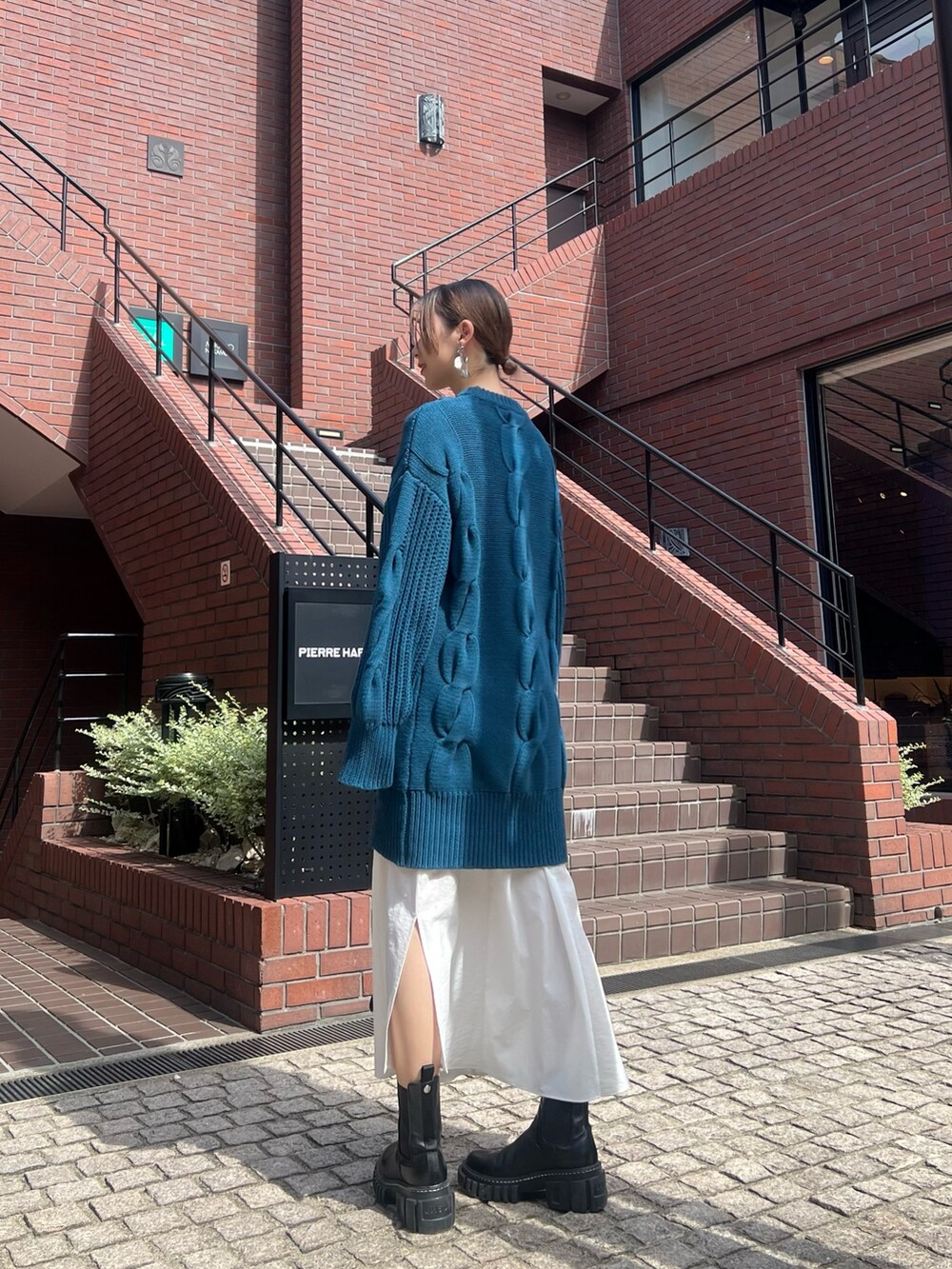 ブルー系のワンピース、ブラック系のブーツ、シルバー系のイヤリングを着用したレディースの秋コーディネートの2枚目の写真