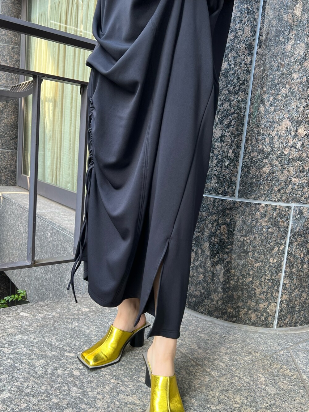 ブラック系のワンピース、ゴールド系のパンプス、ゴールド系のイヤリングを着用したレディースの冬コーディネートの4枚目の写真