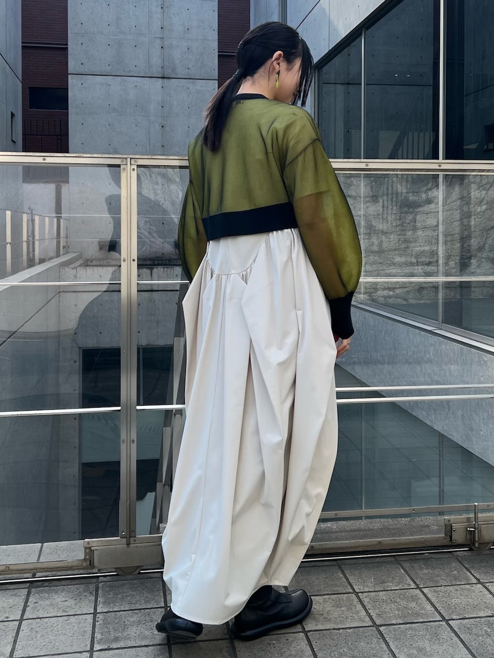 イエロー系のカーディガン/ボレロ、ベージュ系のワンピース、ブラック系のブーツを着用したレディースの冬コーディネートの2枚目の写真