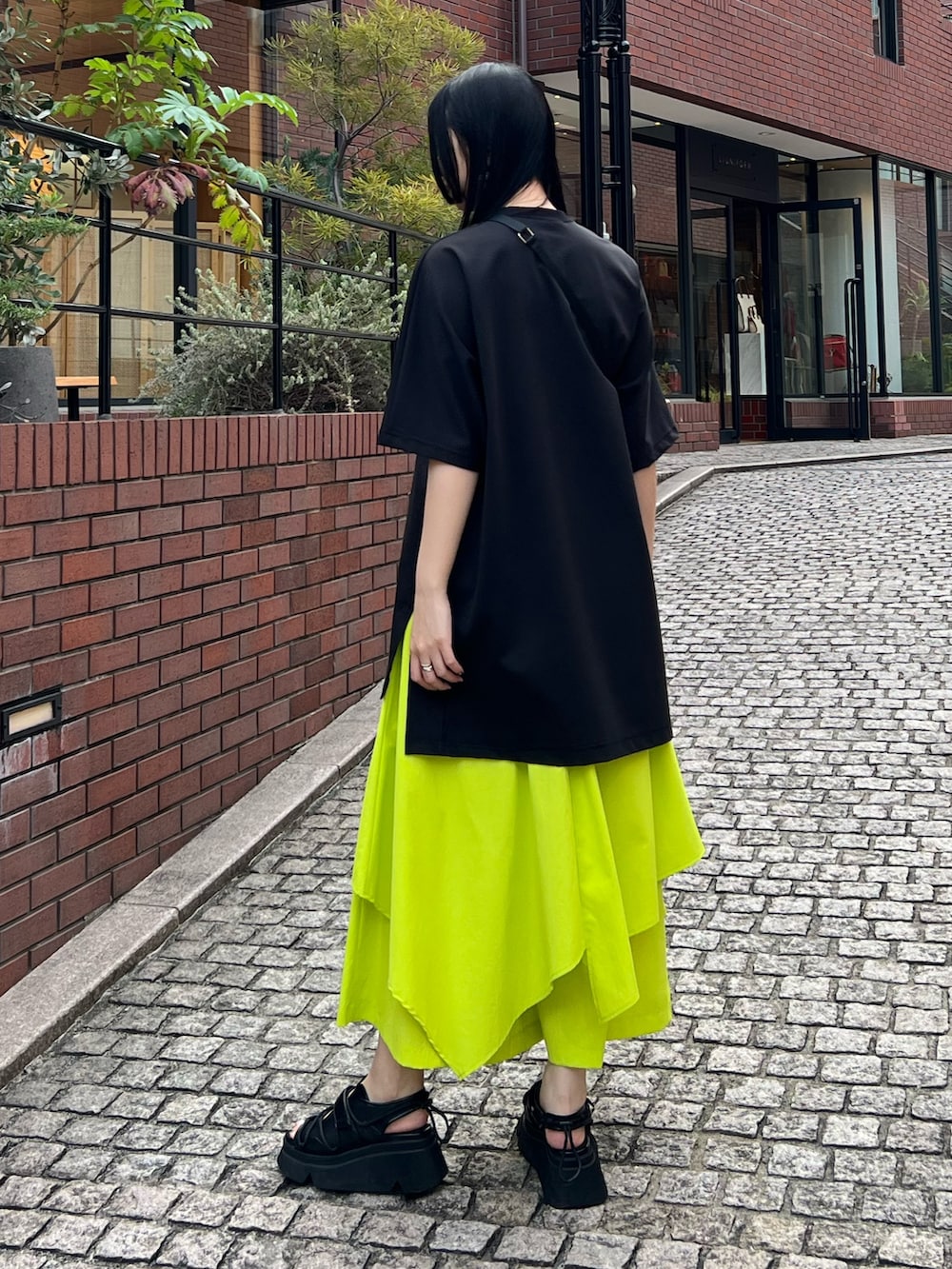 ブラック系のTシャツ/カットソー、イエロー系のその他パンツ、ブラック系のサンダルを着用したレディースの春コーディネートの2枚目の写真