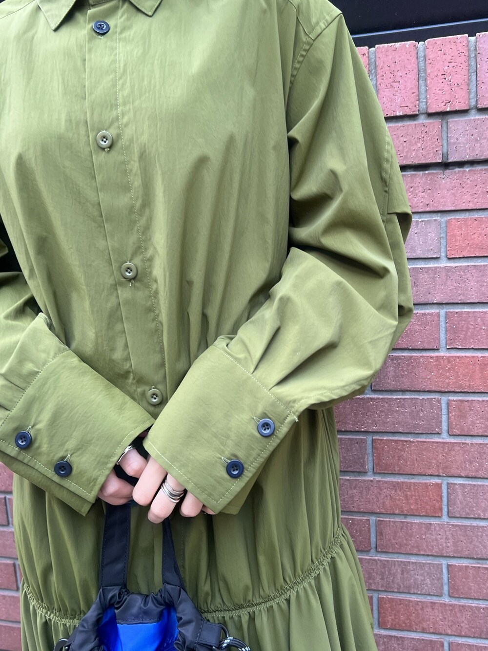 グリーン系のワンピース、ブラック系のブーツ、レッド系のイヤリングを着用したレディースの冬コーディネートの4枚目の写真