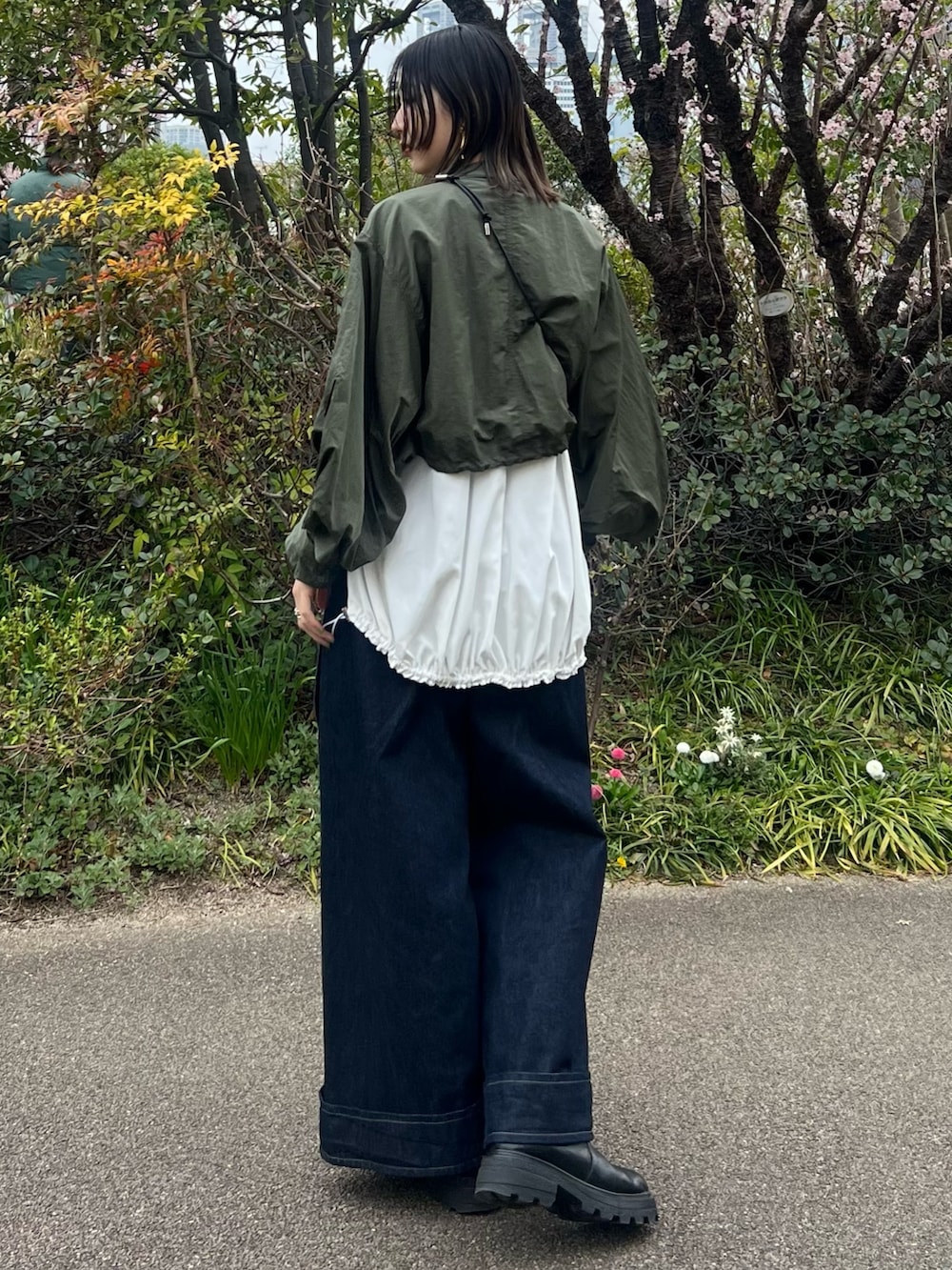 グリーン系のブルゾン、ホワイト系のTシャツ/カットソー、ブルー系のデニムパンツを着用したレディースの春コーディネートの2枚目の写真