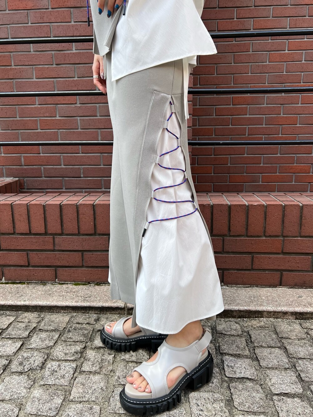 ベージュ系のニット/セーター、ベージュ系のスカート、ベージュ系のサンダルを着用したレディースの春コーディネートの6枚目の写真