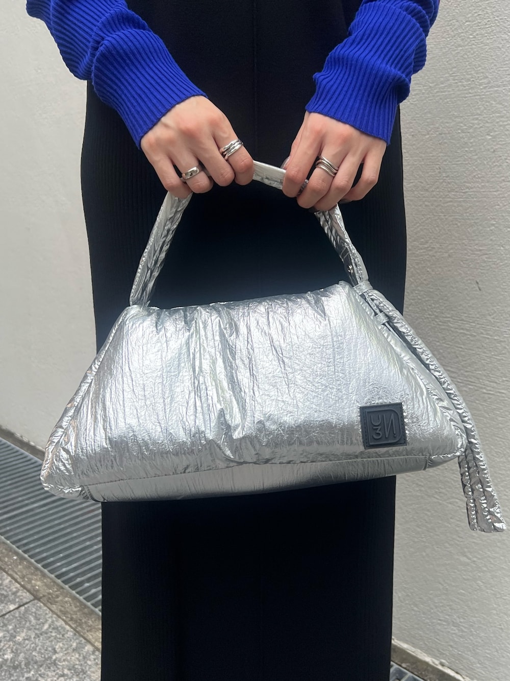 ブラック系のワンピース、シルバー系のハンドバッグ、ブラック系のブーツを着用したレディースの秋コーディネートの6枚目の写真