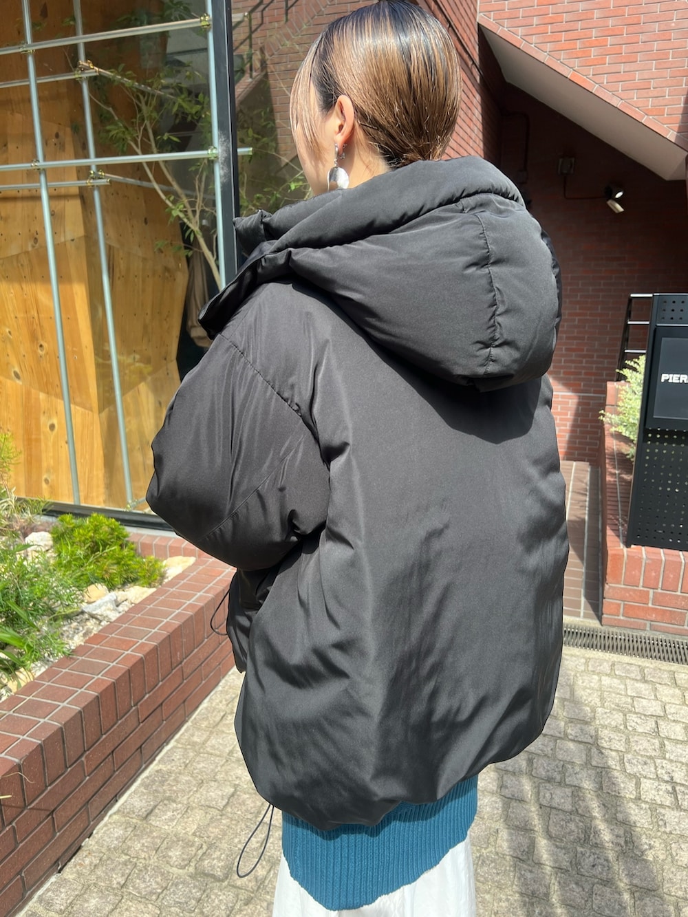 ブラック系のダウンジャケット/コート、ブルー系のワンピース、ブラック系のブーツを着用したレディースの秋コーディネートの3枚目の写真