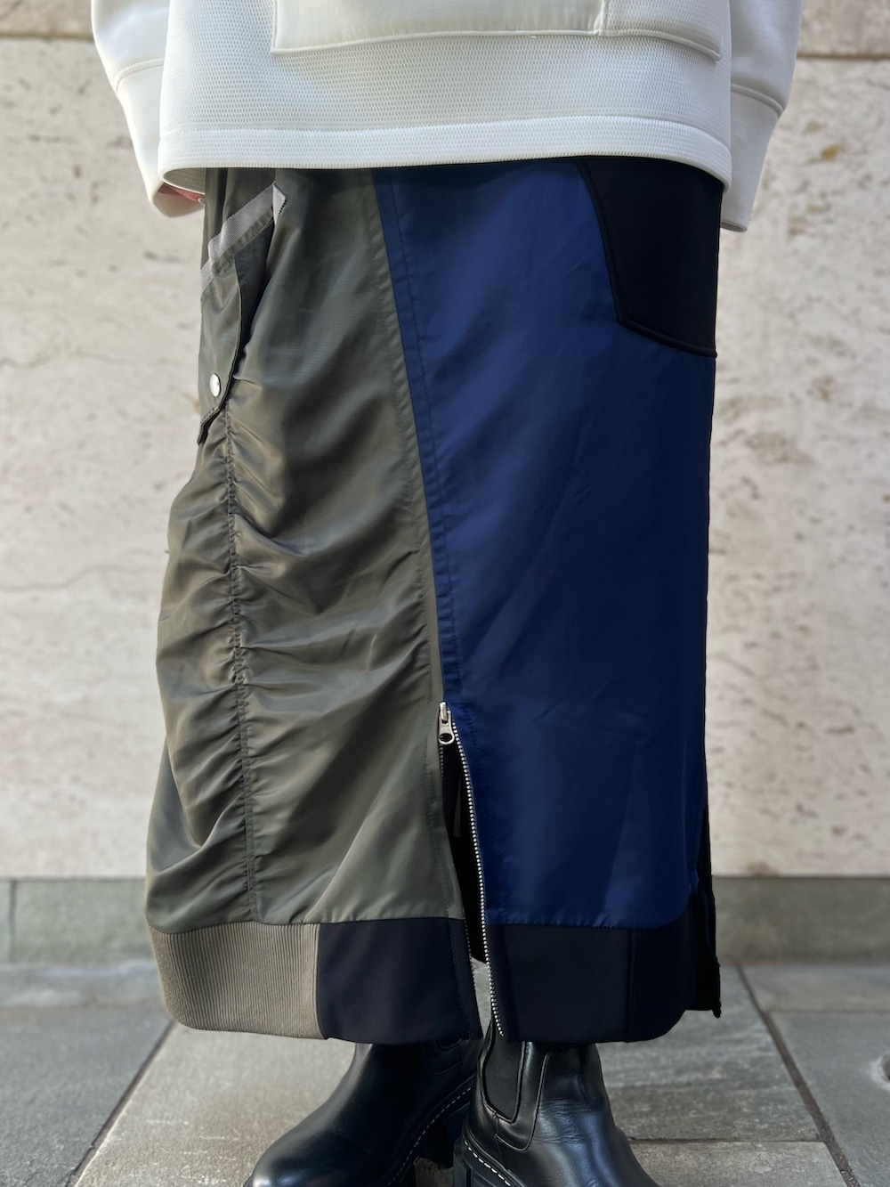 ブラック系のスカート、ホワイト系のスウェット、ブラック系のブーツを着用したレディースの秋コーディネートの9枚目の写真