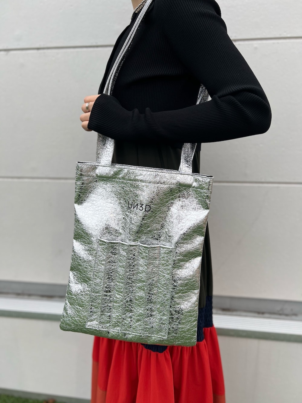 オレンジ系のワンピース、ブラック系のカーディガン/ボレロ、シルバー系のネックレスを着用したレディースの春コーディネートの5枚目の写真