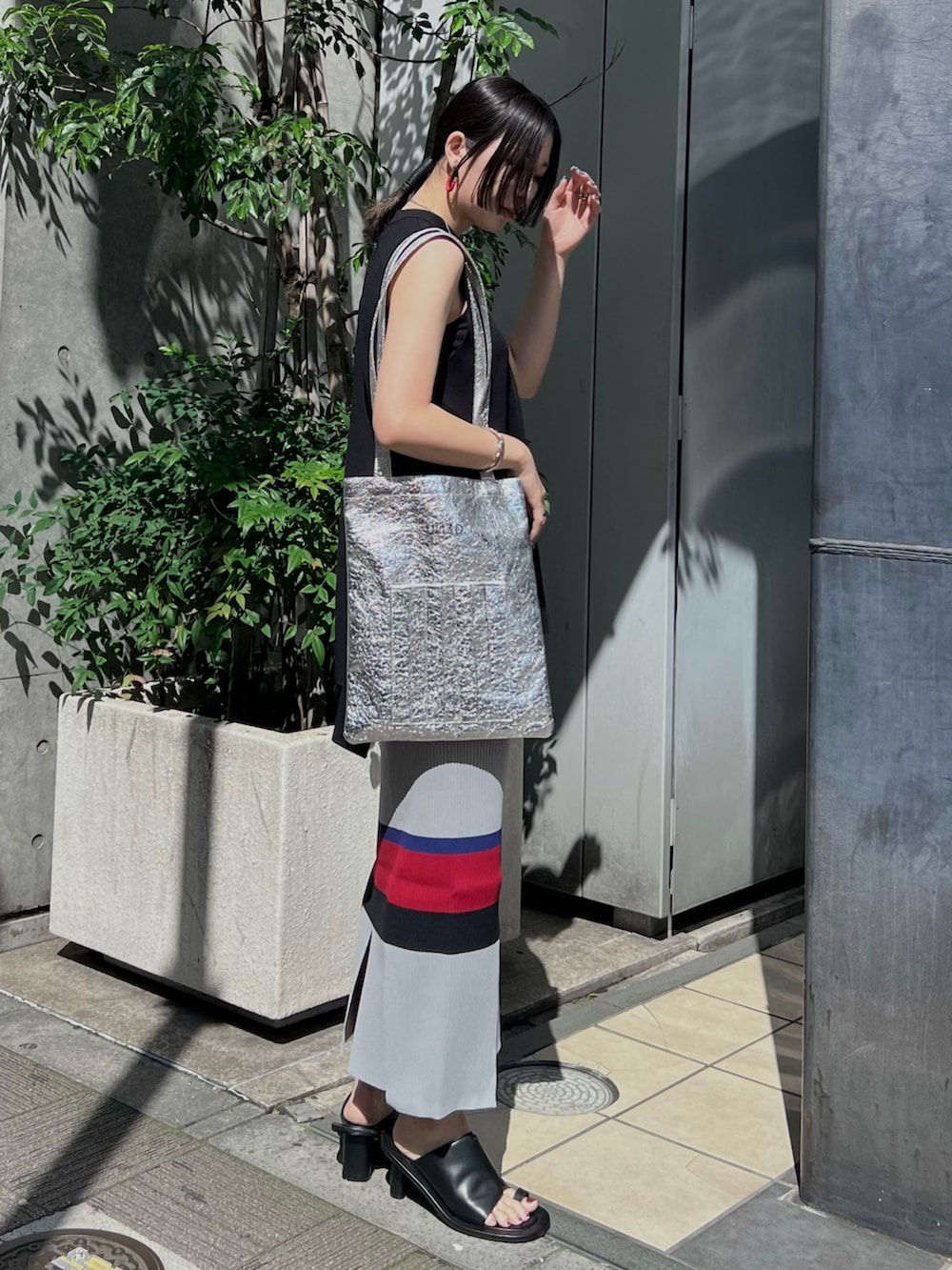 ブラック系のニット/セーター、ブラック系のスカート、シルバー系のトートバッグを着用したレディースの夏コーディネートの3枚目の写真