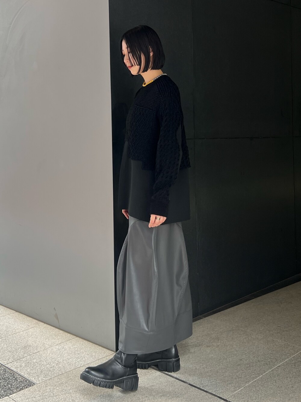 ブラック系のニット/セーター、グレー系のスカート、ブラック系のブーツを着用したレディースの秋コーディネートの2枚目の写真