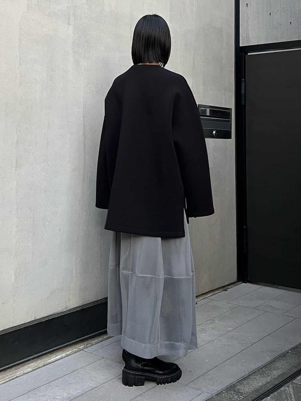 ブラック系のTシャツ/カットソー、グレー系のスカート、ブラック系のブーツを着用したレディースの冬コーディネートの3枚目の写真