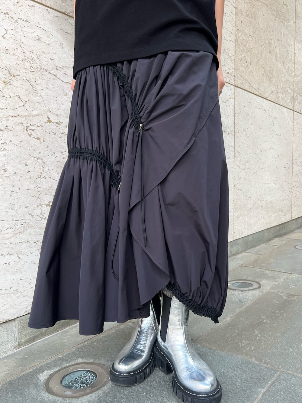 ブラック系のスカート、ブラック系のTシャツ/カットソー、シルバー系のブーツを着用したレディースの冬コーディネートの6枚目の写真