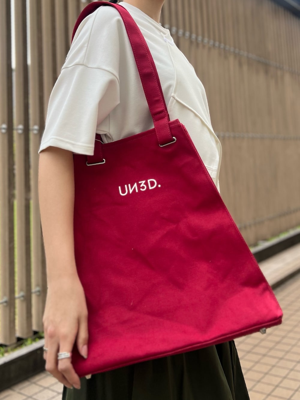 ホワイト系のTシャツ/カットソー、グリーン系のスカート、レッド系のトートバッグを着用したレディースの春コーディネートの3枚目の写真