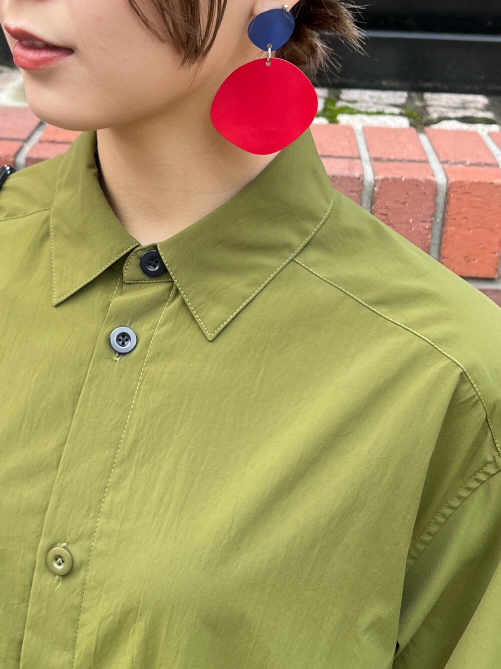 グリーン系のワンピース、ブラック系のブーツ、レッド系のイヤリングを着用したレディースの冬コーディネートの7枚目の写真