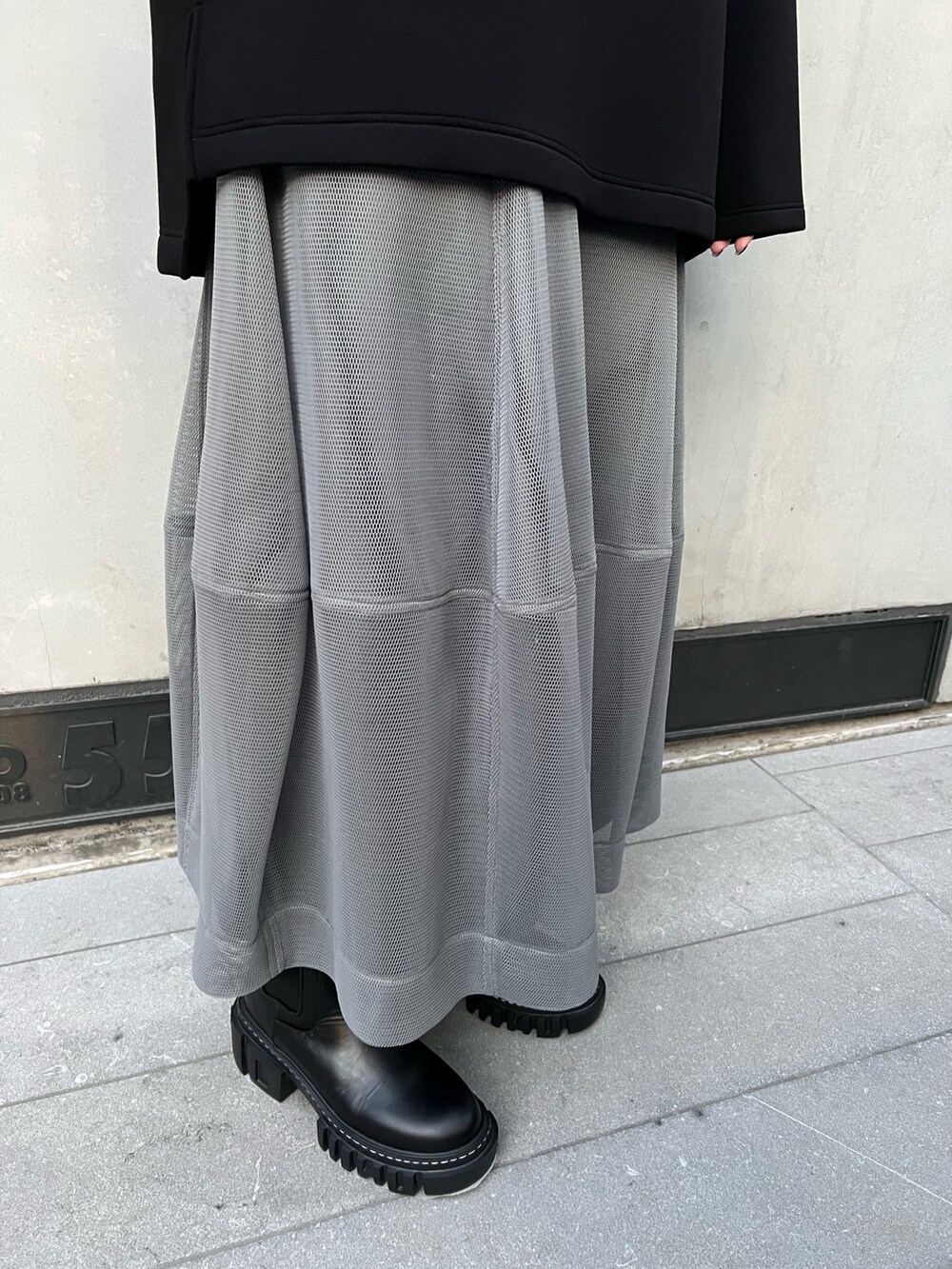 ブラック系のTシャツ/カットソー、グレー系のスカート、ブラック系のブーツを着用したレディースの冬コーディネートの6枚目の写真