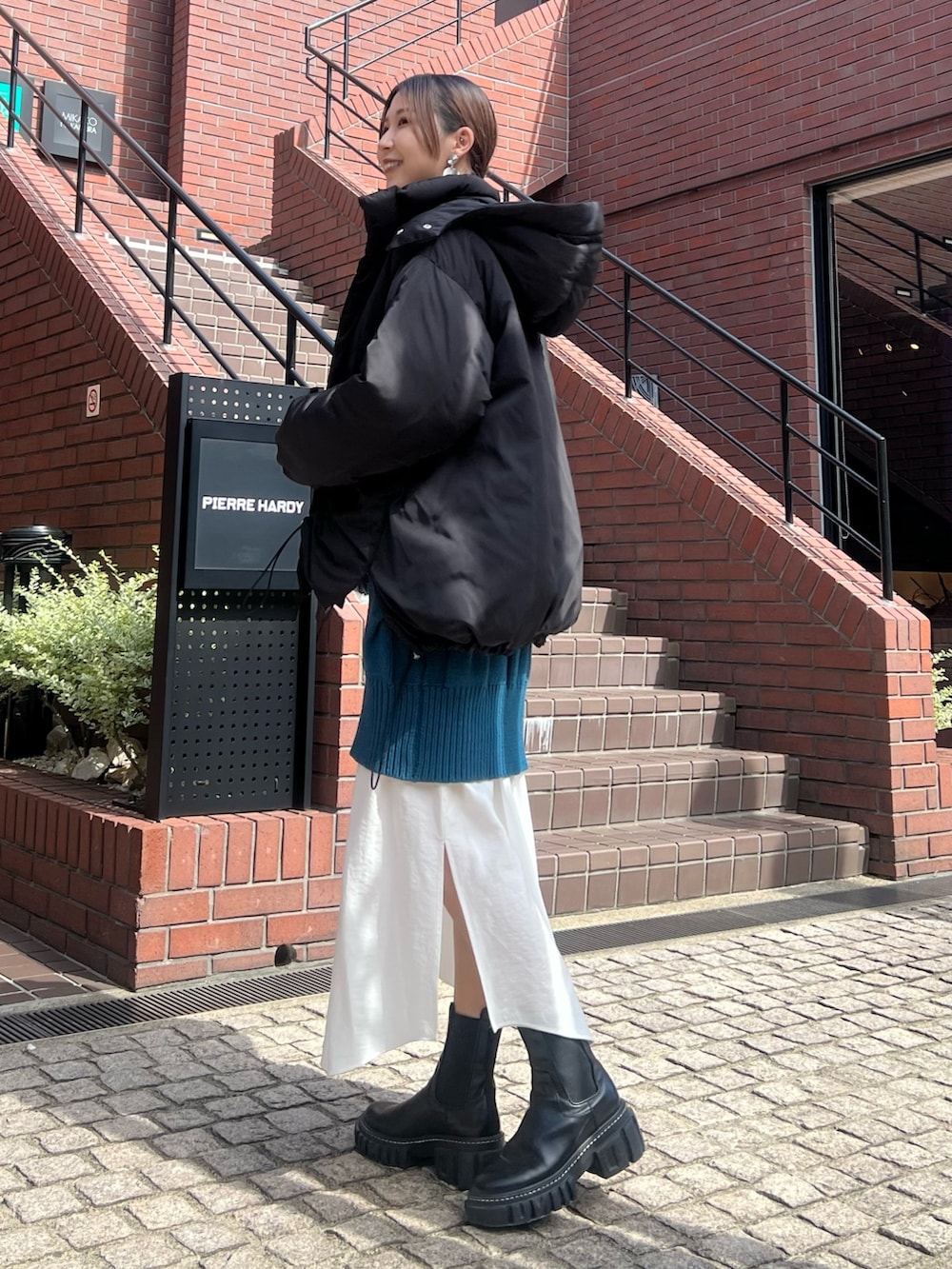 ブラック系のダウンジャケット/コート、ブルー系のワンピース、ブラック系のブーツを着用したレディースの秋コーディネートの2枚目の写真