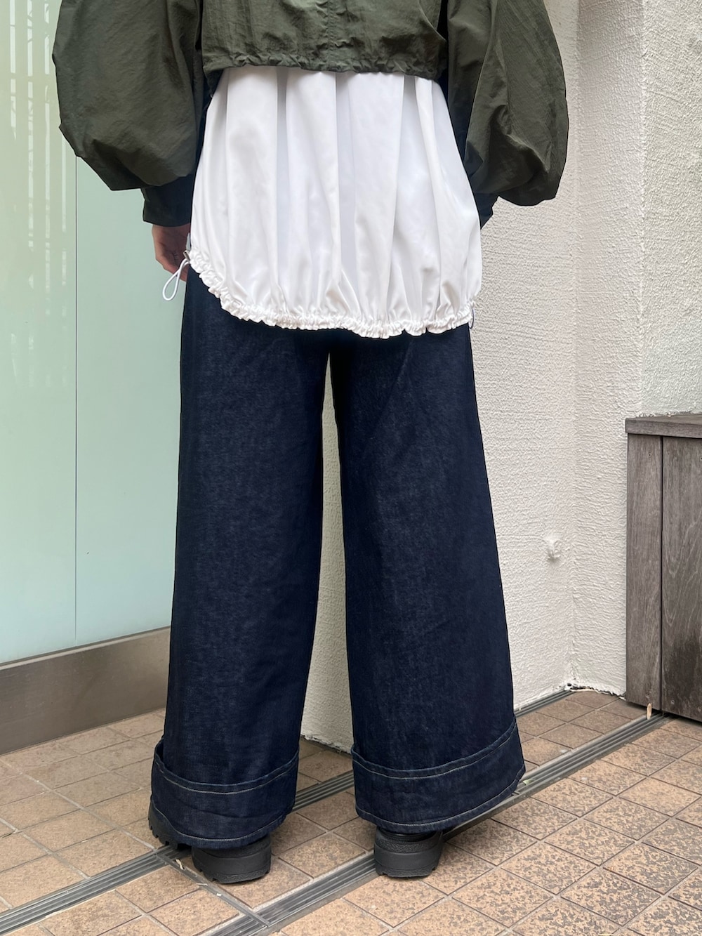 グリーン系のブルゾン、ホワイト系のTシャツ/カットソー、ブルー系のデニムパンツを着用したレディースの春コーディネートの7枚目の写真