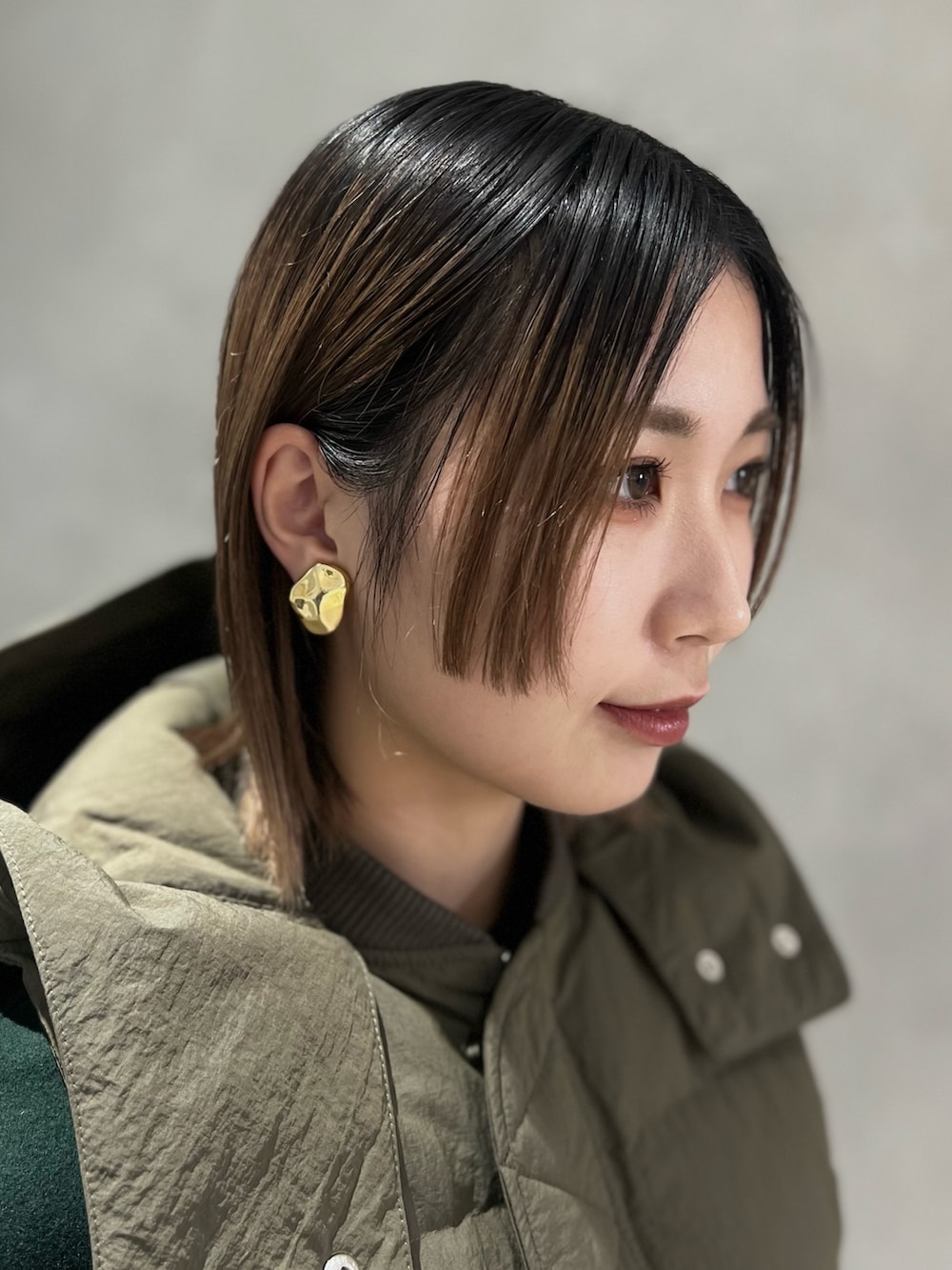 グリーン系のダウンベスト、グリーン系のその他アウター、シルバー系のイヤリングを着用したレディースの秋コーディネートの8枚目の写真