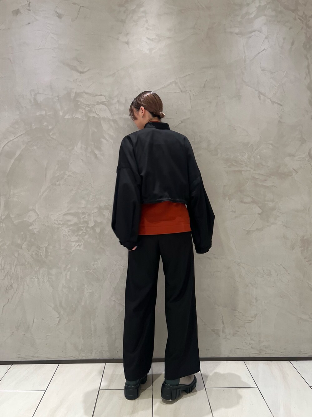 ブラック系のブルゾン、オレンジ系のニット/セーター、ブラック系のその他パンツを着用したレディースの秋コーディネートの3枚目の写真