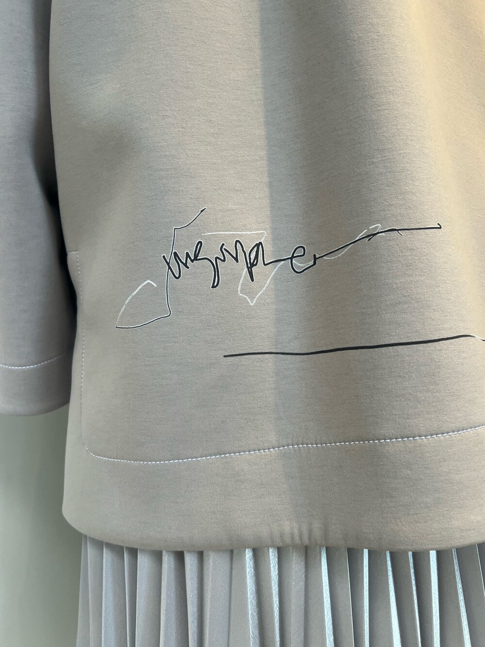 シルバー系のスカート、ベージュ系のTシャツ/カットソー、ブラック系のブーツを着用したレディースの冬コーディネートの6枚目の写真