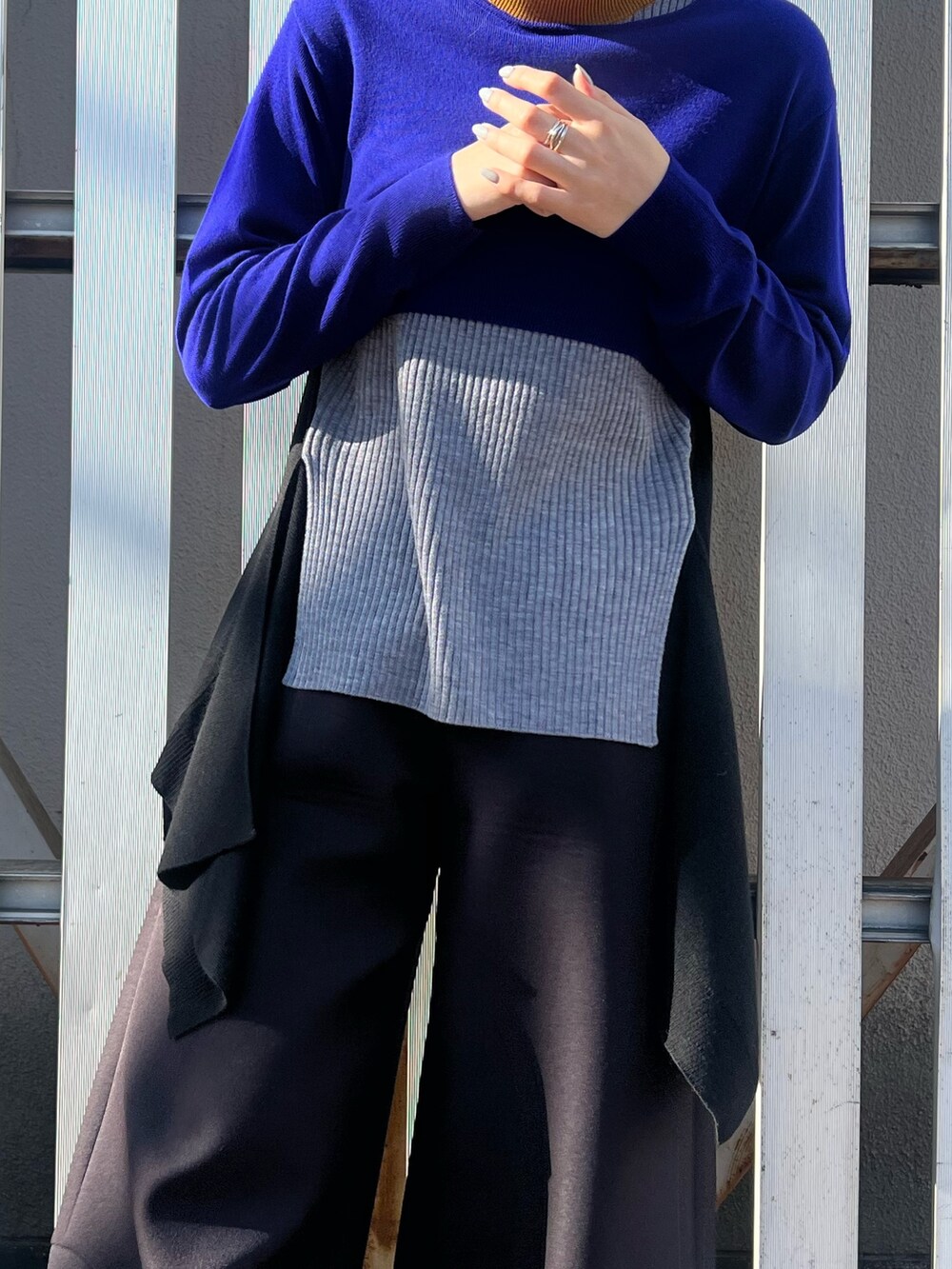 ブルー系のニット/セーター、ブラック系のその他パンツ、シルバー系のイヤリングを着用したレディースの冬コーディネートの6枚目の写真
