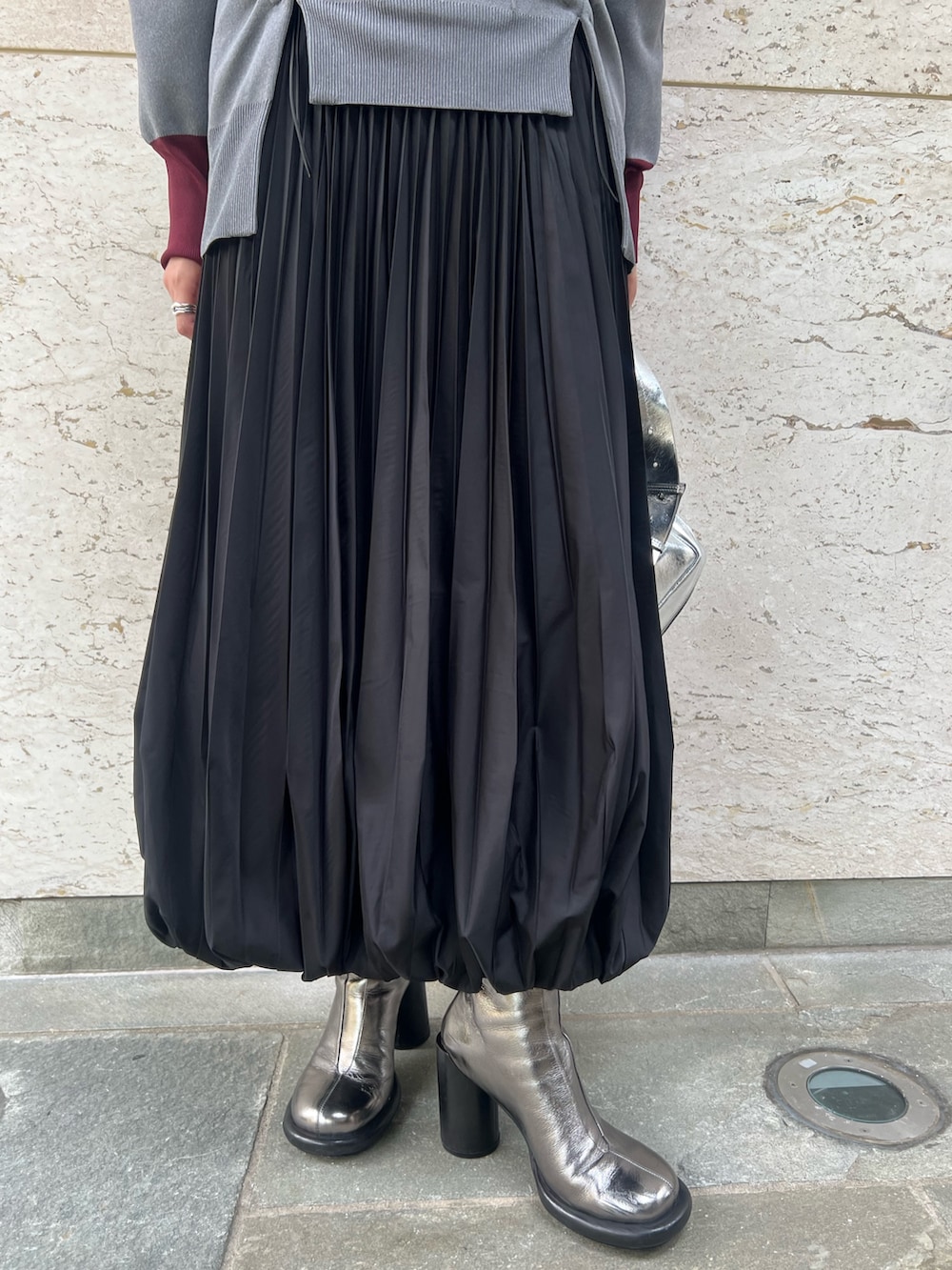 シルバー系のブーツ、ブラック系のスカート、グレー系のニット/セーターを着用したレディースの秋コーディネートの6枚目の写真