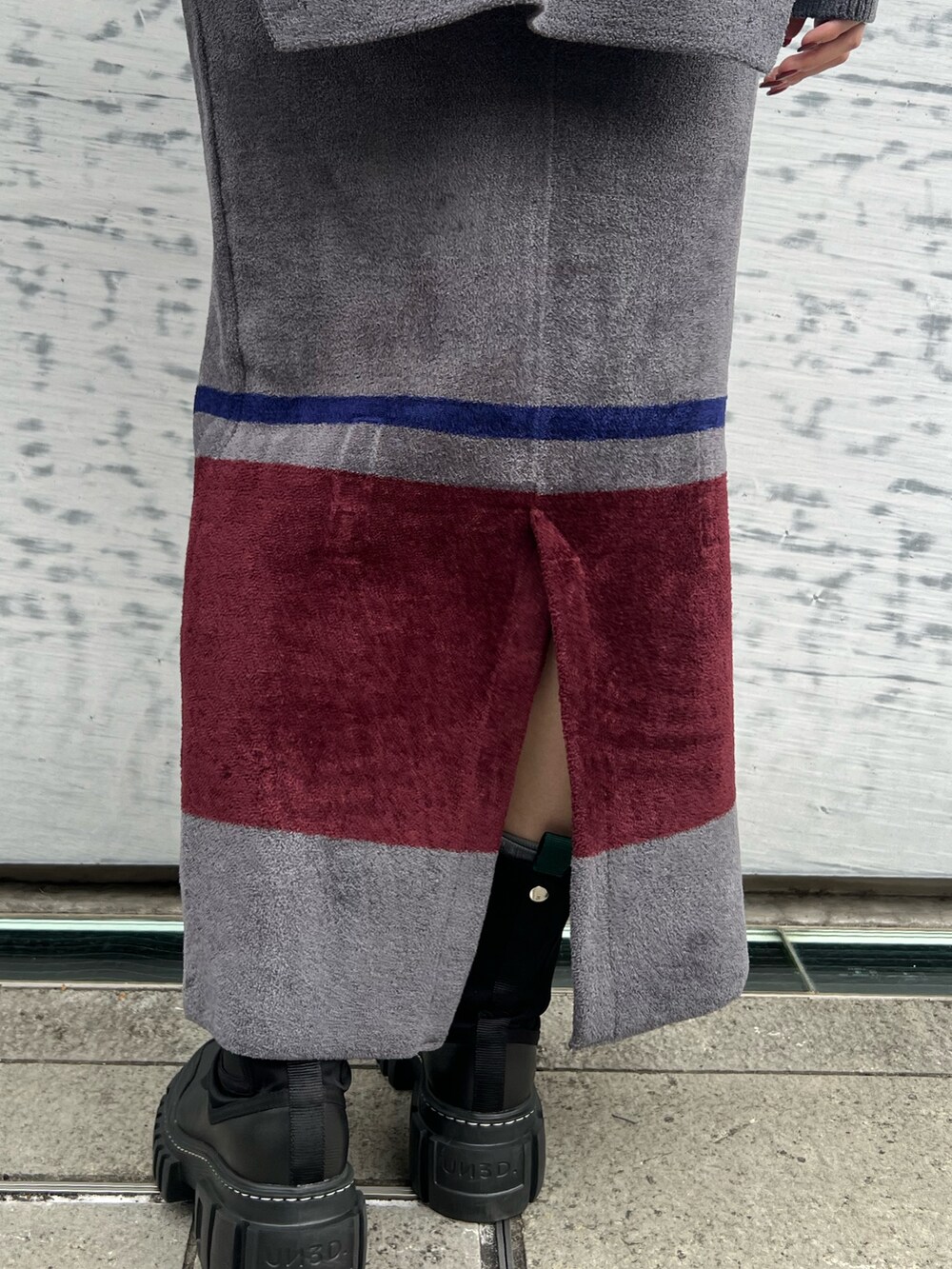 グレー系のニット/セーター、グレー系のスカート、ブラック系のブーツを着用したレディースの冬コーディネートの8枚目の写真