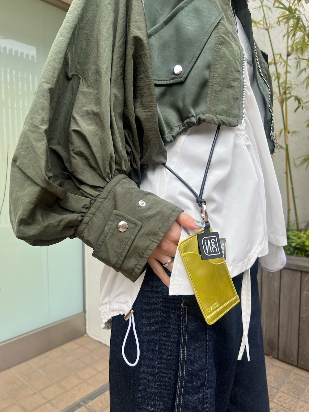 グリーン系のブルゾン、ホワイト系のTシャツ/カットソー、ブルー系のデニムパンツを着用したレディースの春コーディネートの4枚目の写真