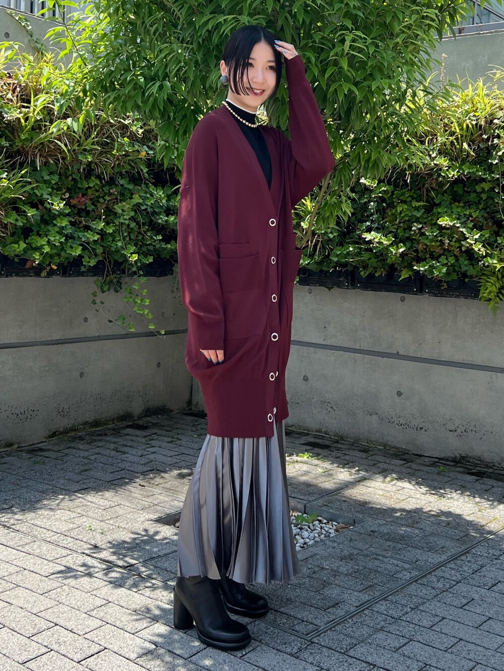 グレー系のスカート、ブラウン系のカーディガン/ボレロ、ブラック系のニット/セーターを着用したレディースの夏コーディネートの2枚目の写真