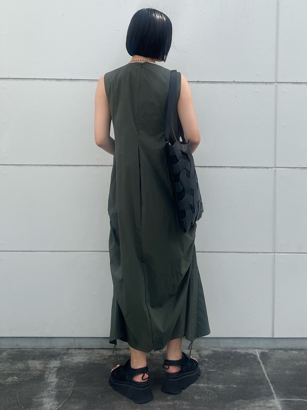 グリーン系のワンピース、ブラック系のトートバッグ、ブラック系のサンダルを着用したレディースの夏コーディネートの2枚目の写真