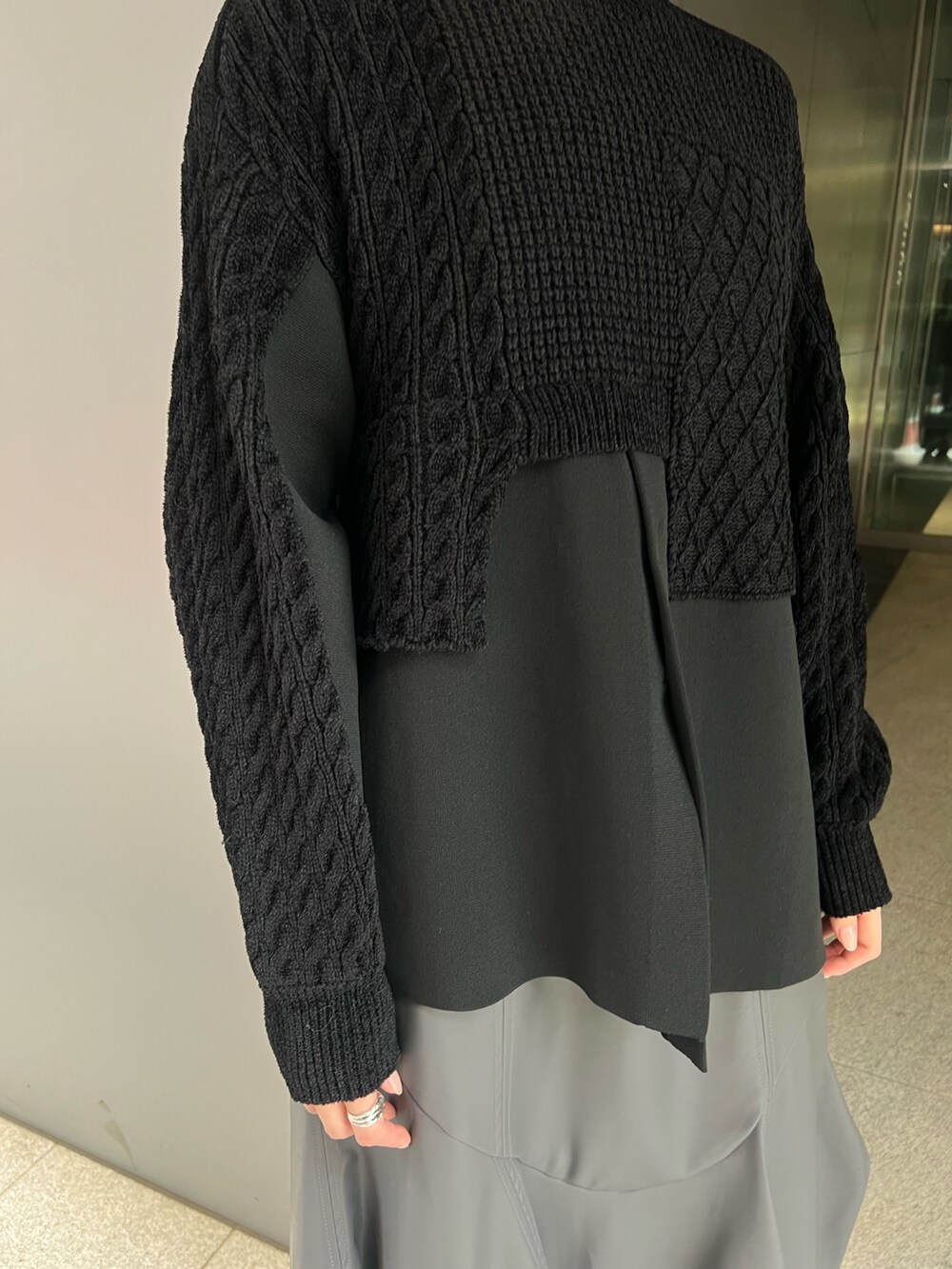 ブラック系のニット/セーター、グレー系のスカート、ブラック系のブーツを着用したレディースの秋コーディネートの5枚目の写真