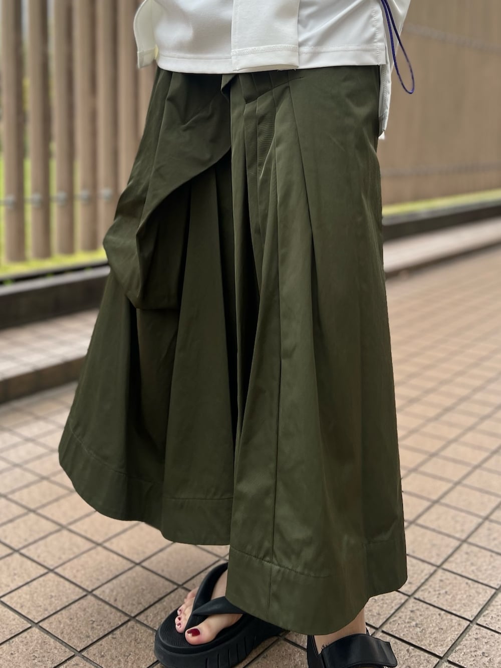 ホワイト系のTシャツ/カットソー、グリーン系のスカート、レッド系のトートバッグを着用したレディースの春コーディネートの6枚目の写真