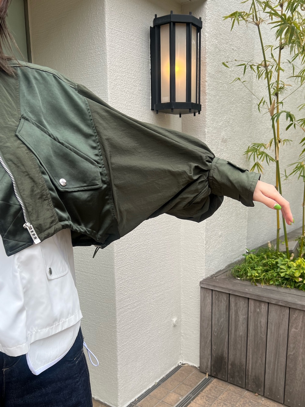 グリーン系のブルゾン、ホワイト系のTシャツ/カットソー、ブルー系のデニムパンツを着用したレディースの春コーディネートの3枚目の写真