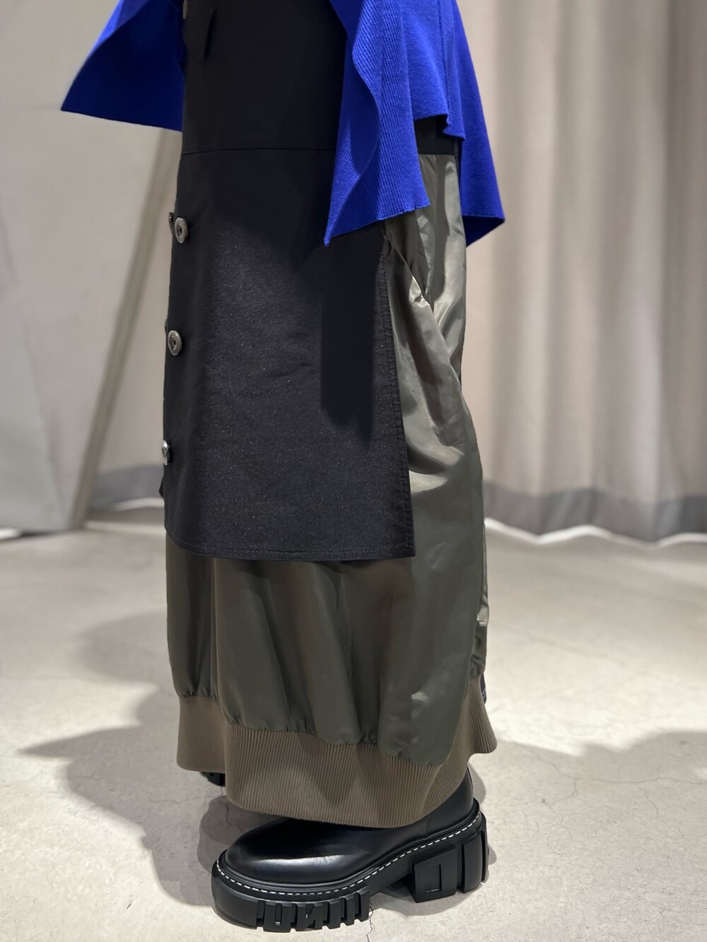 ブルー系のニット/セーター、ブラック系のスカート、ブラック系のブーツを着用したレディースの秋コーディネートの7枚目の写真