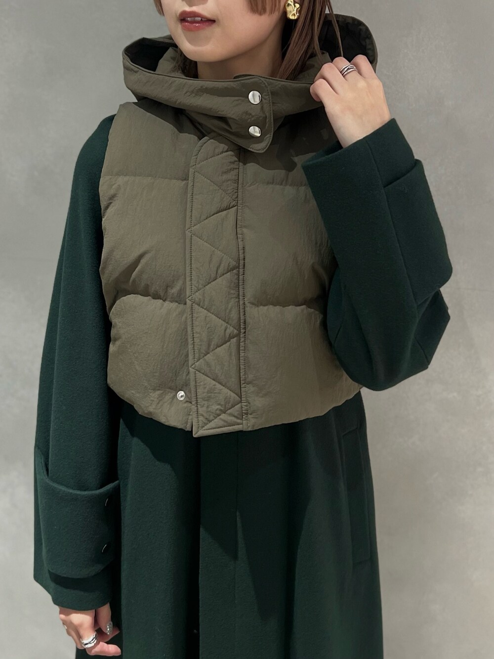 グリーン系のダウンベスト、グリーン系のその他アウター、シルバー系のイヤリングを着用したレディースの秋コーディネートの4枚目の写真