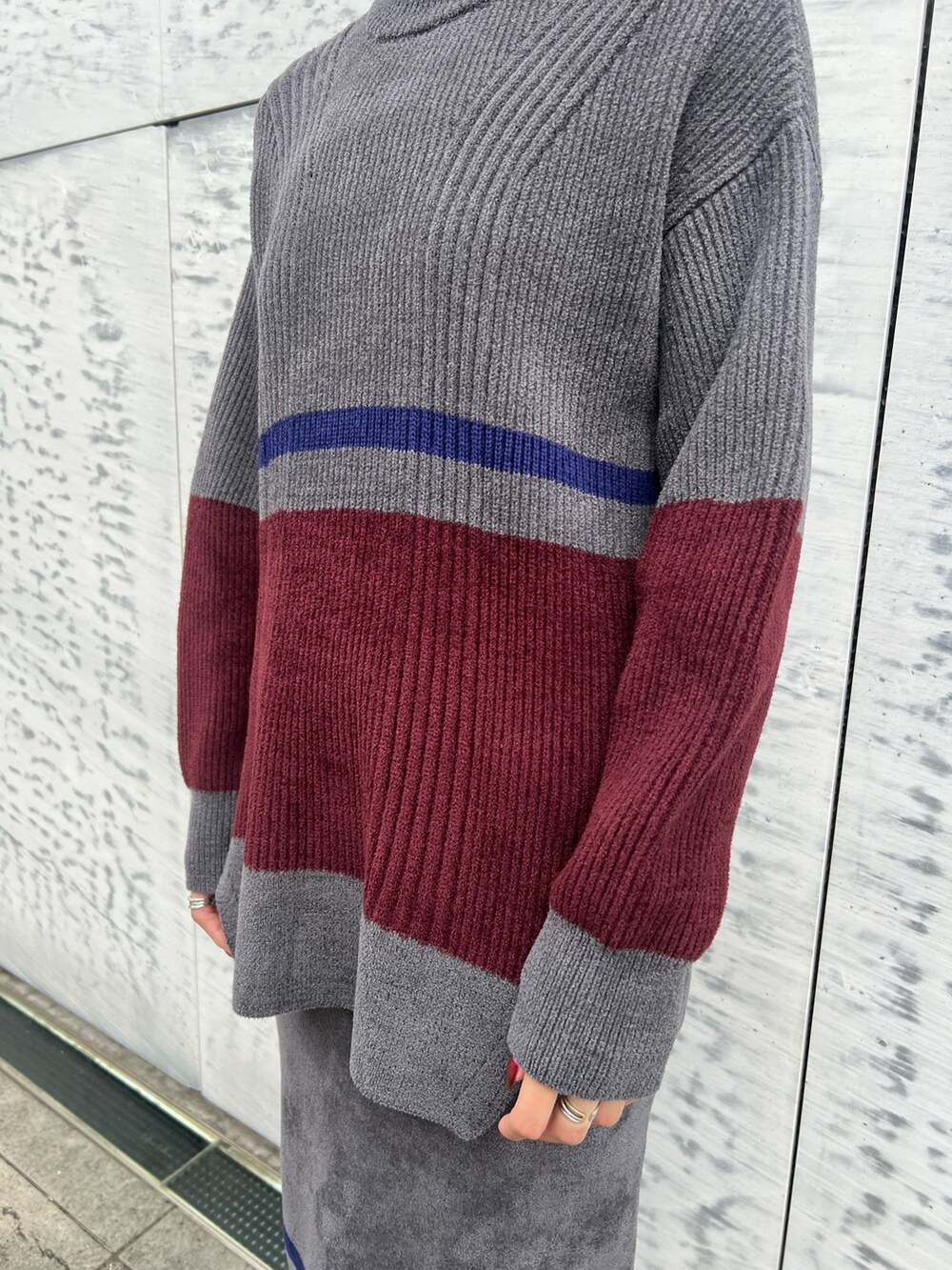 グレー系のニット/セーター、グレー系のスカート、ブラック系のブーツを着用したレディースの冬コーディネートの6枚目の写真