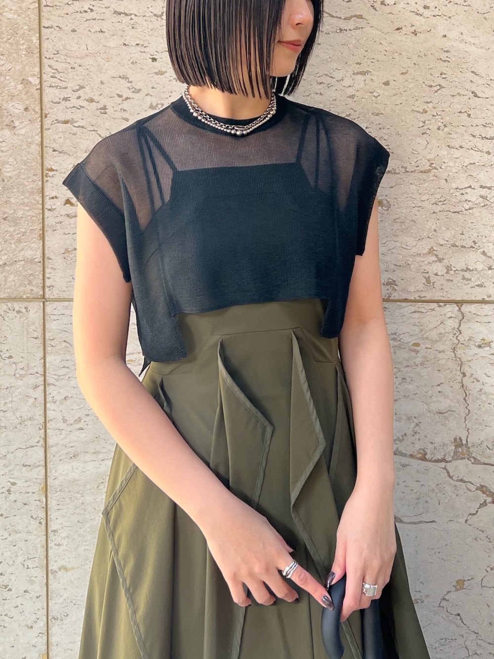 ベージュ系のワンピース、シルバー系のサンダル、ブラック系のニット/セーターを着用したレディースの春コーディネートの3枚目の写真