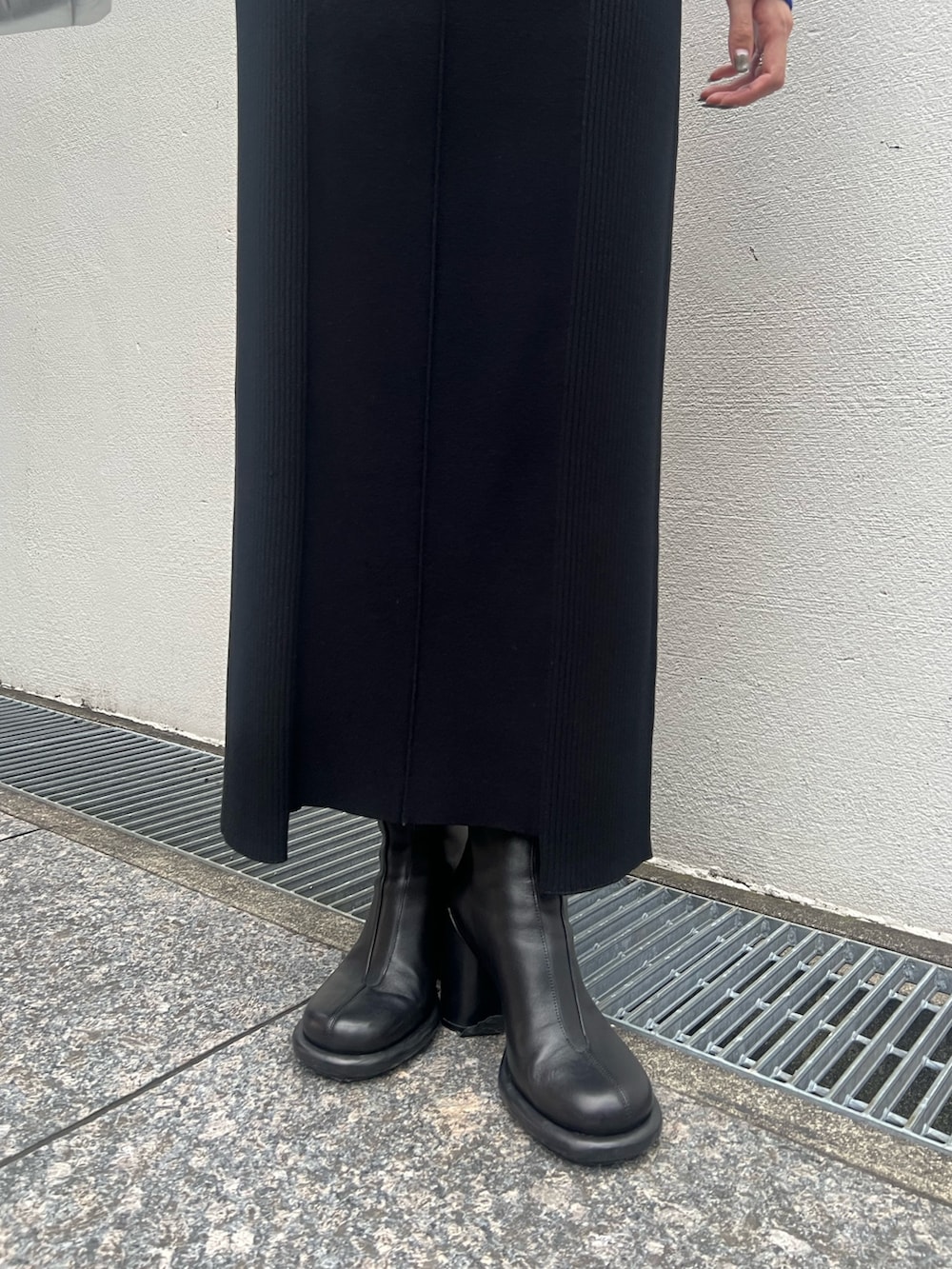 ブラック系のワンピース、シルバー系のハンドバッグ、ブラック系のブーツを着用したレディースの秋コーディネートの7枚目の写真