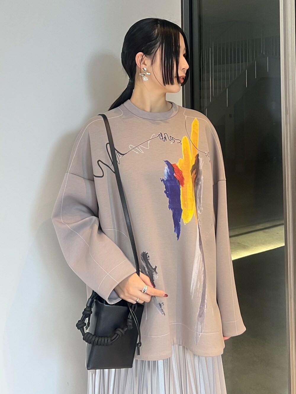 シルバー系のスカート、ベージュ系のTシャツ/カットソー、ブラック系のブーツを着用したレディースの冬コーディネートの3枚目の写真
