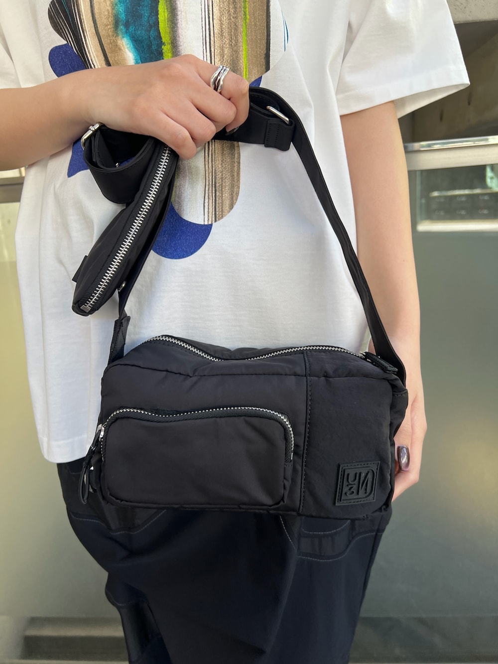 ホワイト系のTシャツ/カットソー、ブラック系のスカート、ブラック系のボディバッグ/ウエストポーチを着用したレディースの春コーディネートの6枚目の写真