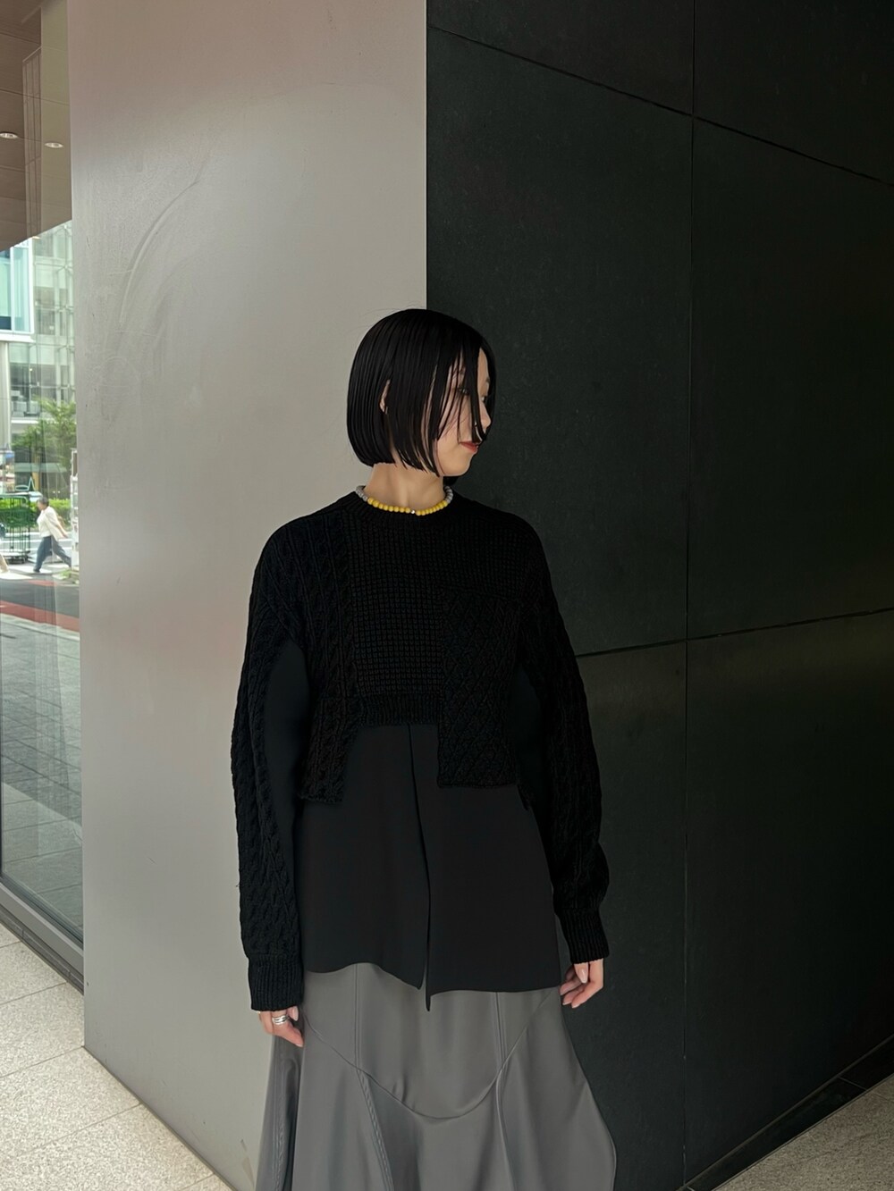 ブラック系のニット/セーター、グレー系のスカート、ブラック系のブーツを着用したレディースの秋コーディネートの4枚目の写真